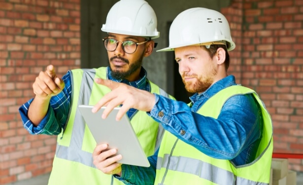 two mean wearing a construction vest and white hard hat